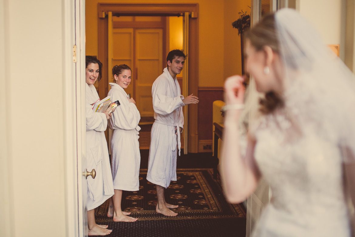 A wedding scene in a hallway with people in white robes getting ready before the ceremony.