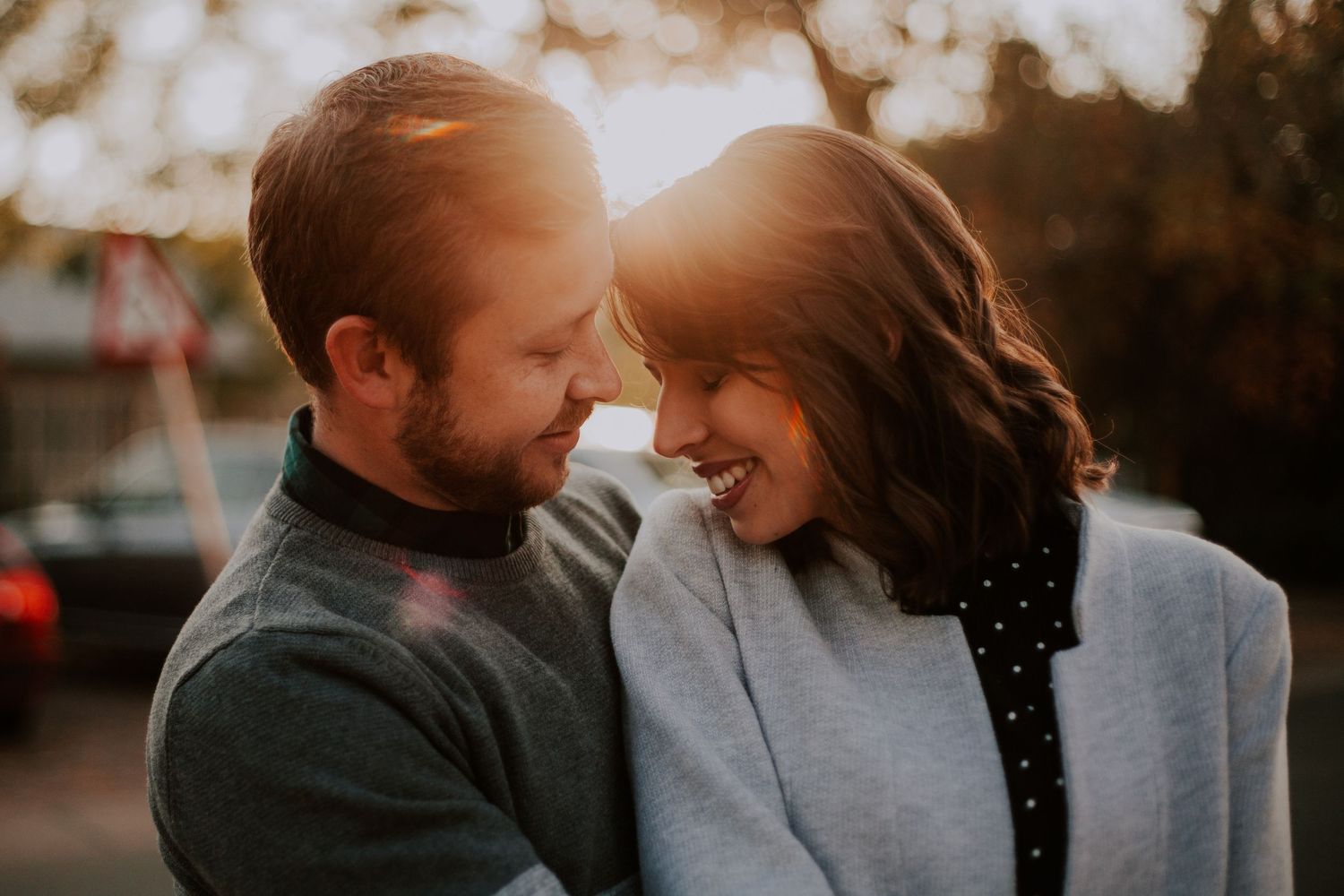 A romantic golden hour moment captured with warm sunlight between a couple sharing an intimate moment outdoors.