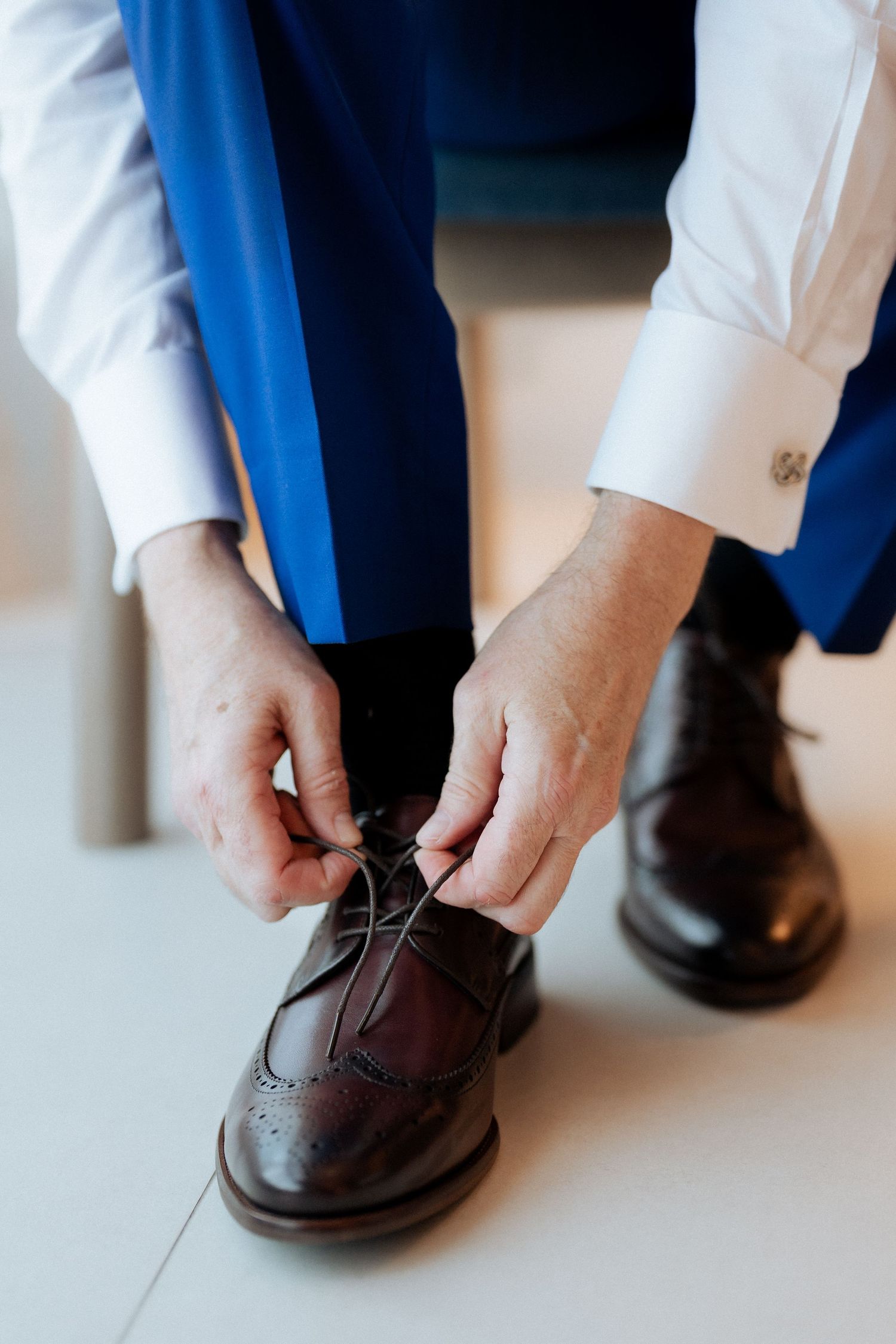 Groom tying wedding shoes during getting ready photos in Dubai