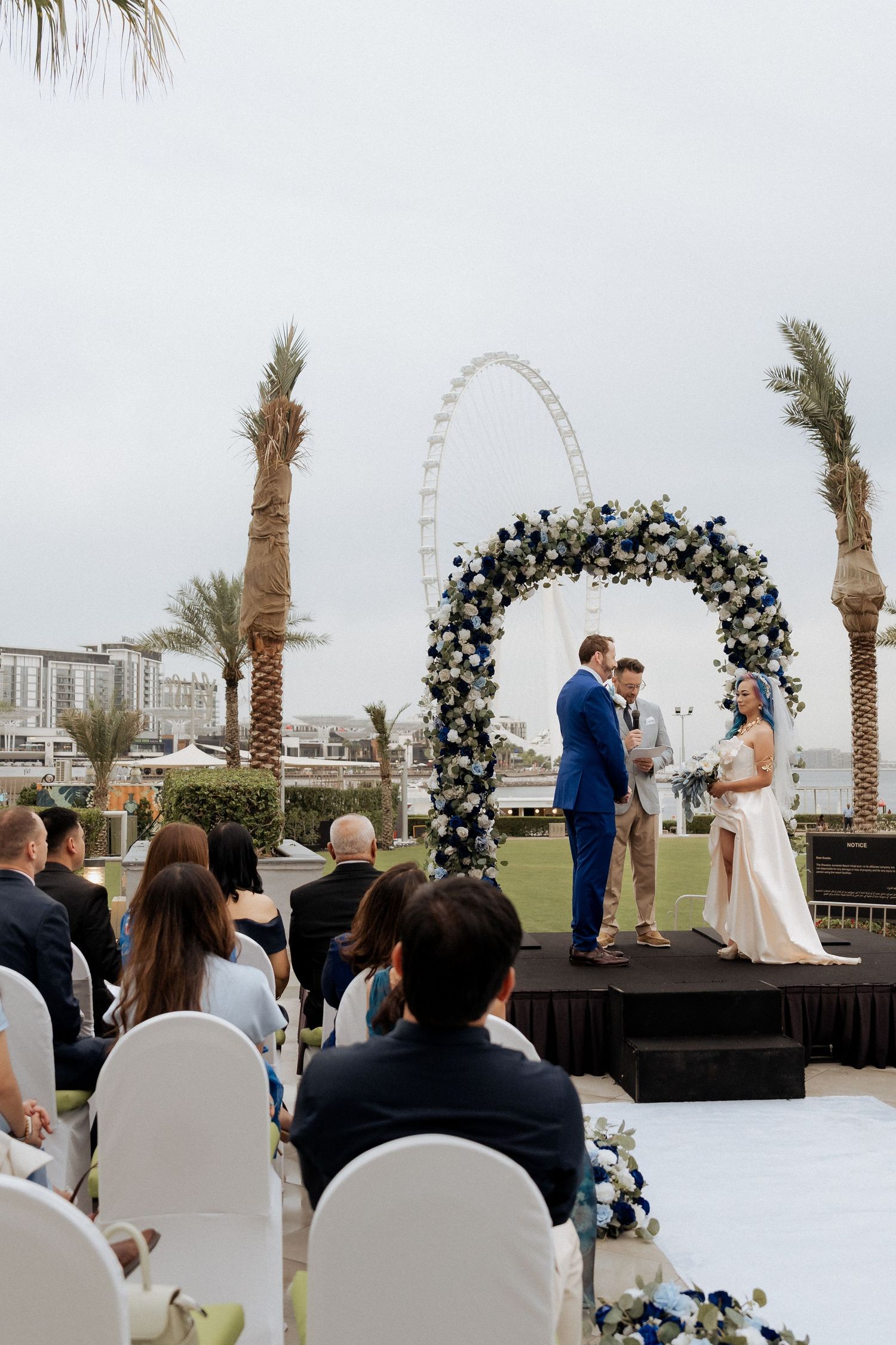 Couple exchanging vows under floral arch during outdoor wedding ceremony in Dubai