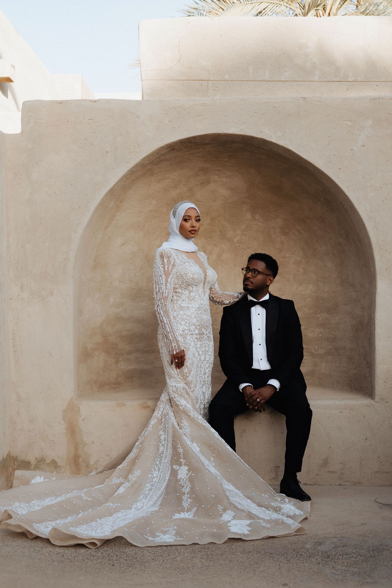 Pre-wedding photoshoot in Dubai – bride in white gown and groom in black suit at archway