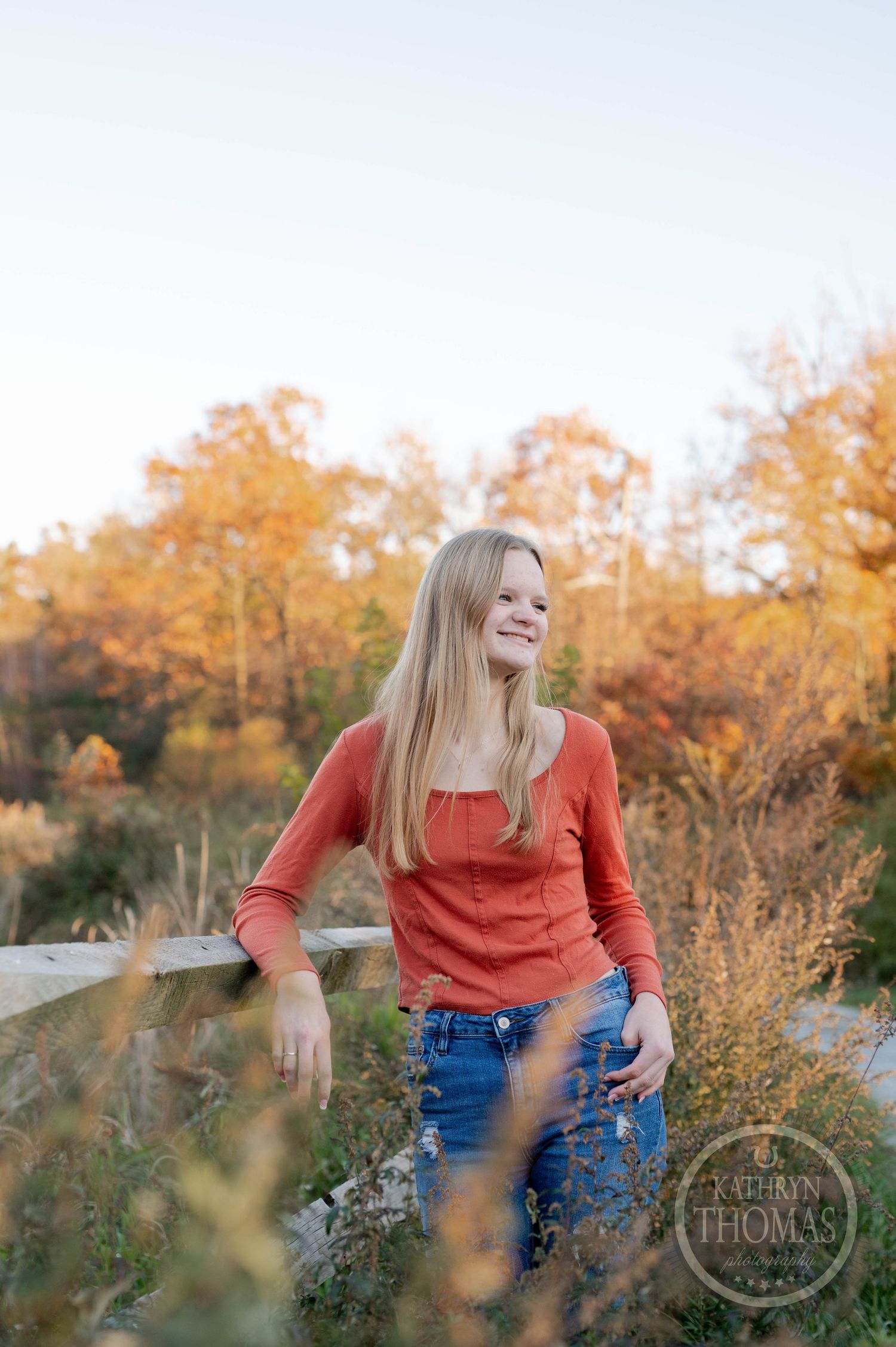 Candid moment captured against wooden fence with wildflowers and fall colors in background.