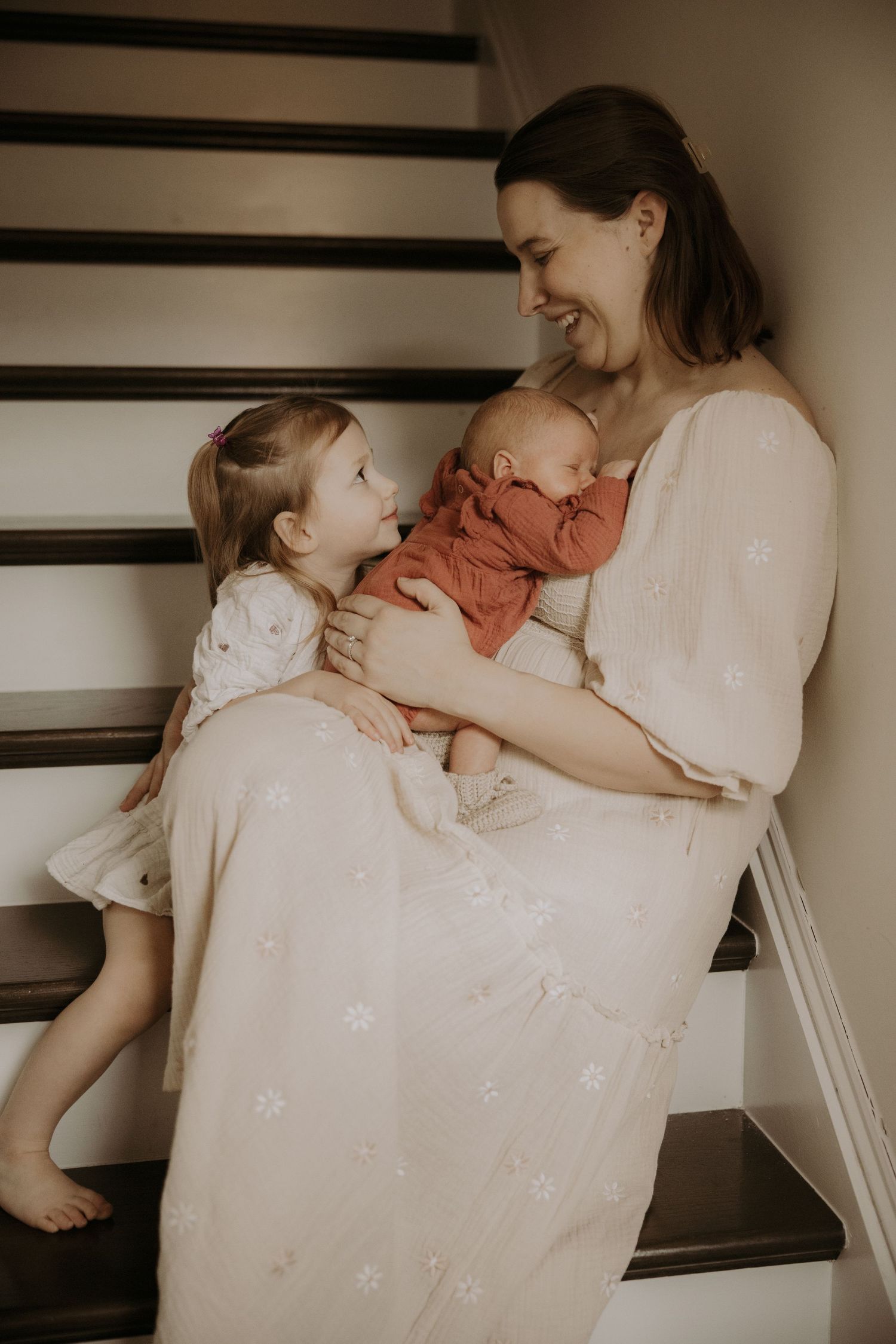 A series of intimate moments showing a parent in white dress holding and bonding with a baby in warm, muted tones.