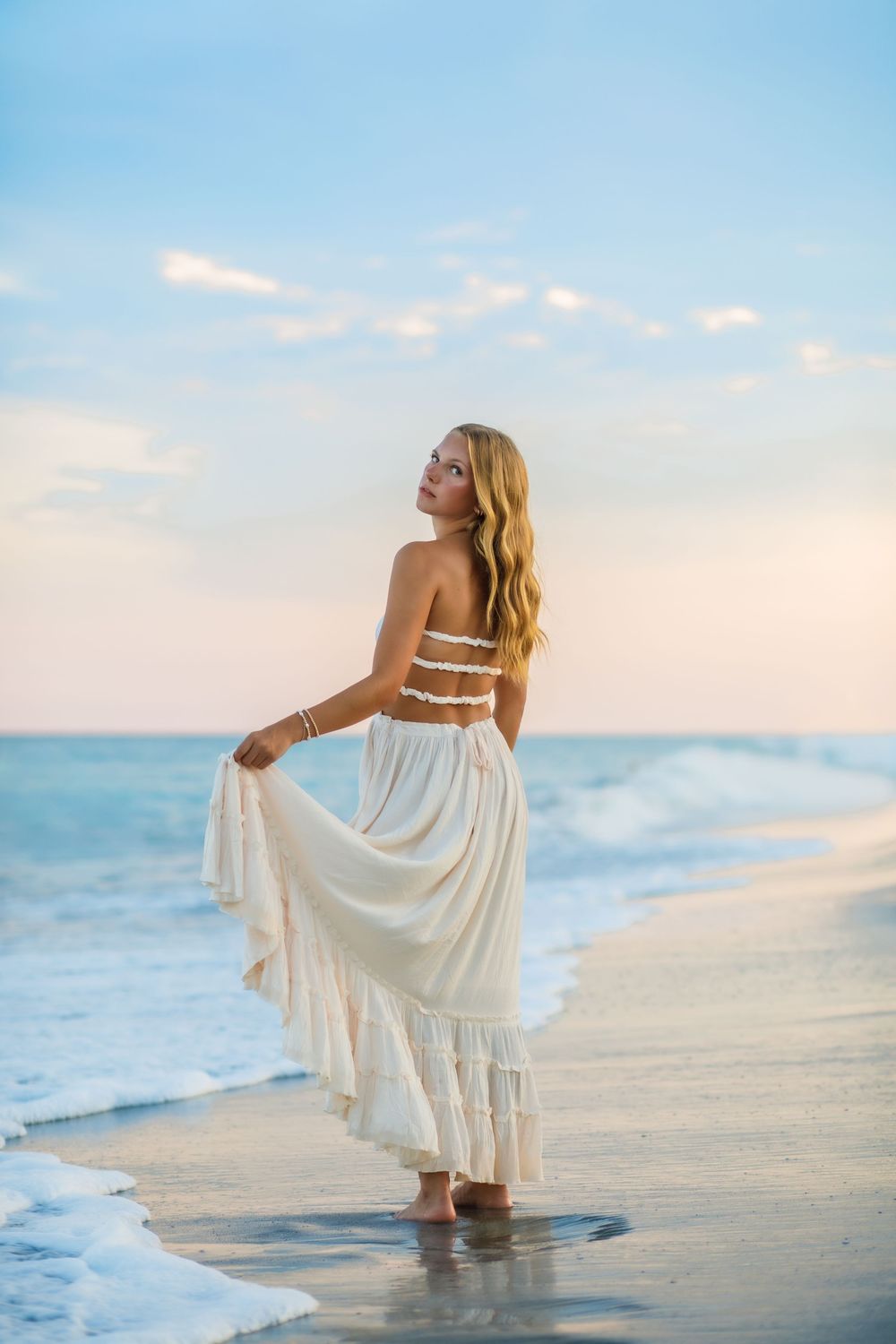 Senior girl enjoying a fun beach photography session in the water at Surf City, NC, captured by a coastal North Carolina senior photographer