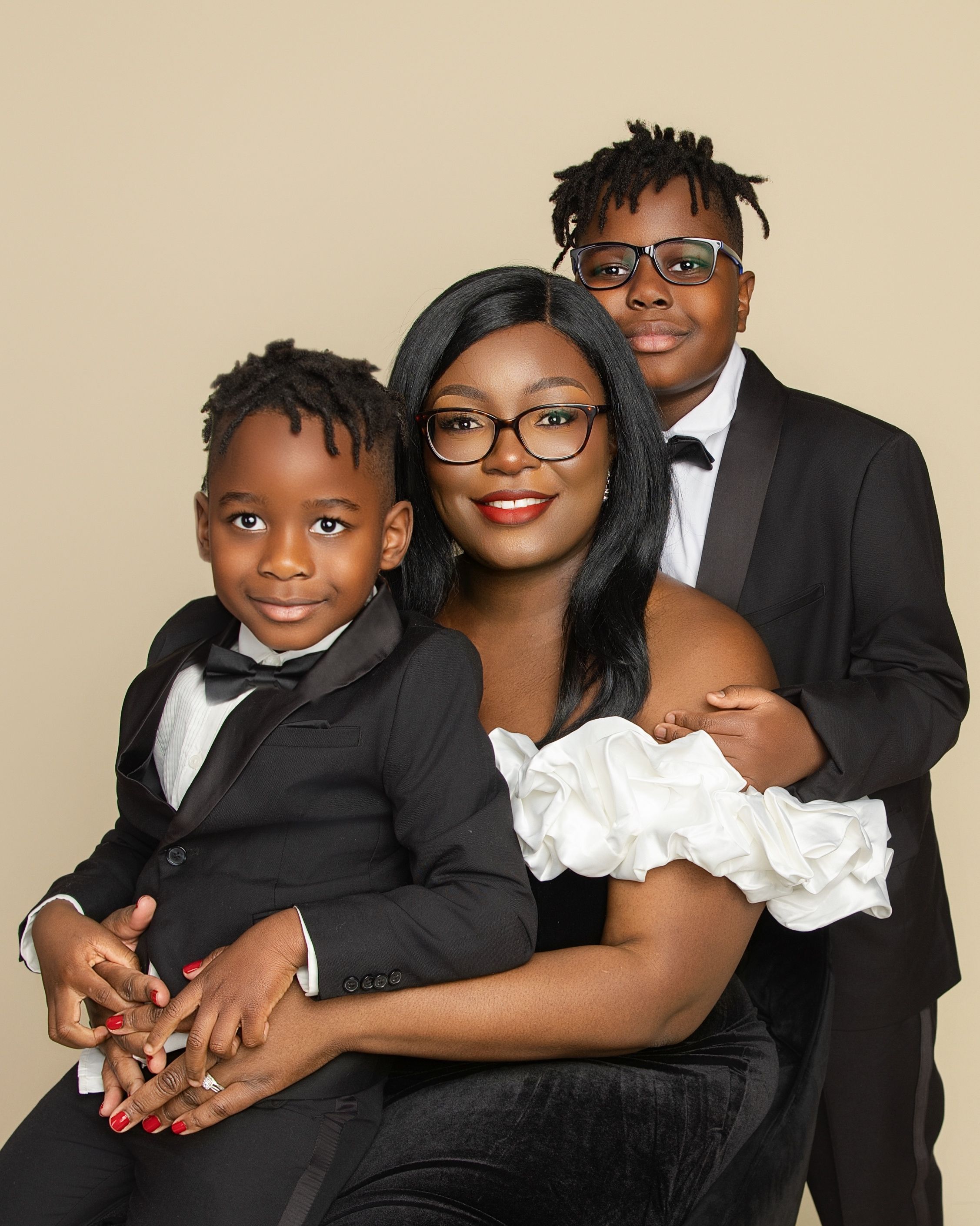A family portrait in formal black and white attire poses together against a neutral backdrop.