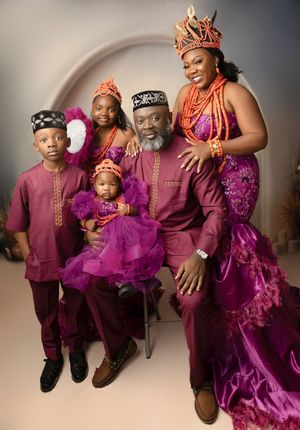 A family poses in coordinating burgundy and purple formal attire for a stylish portrait session.
