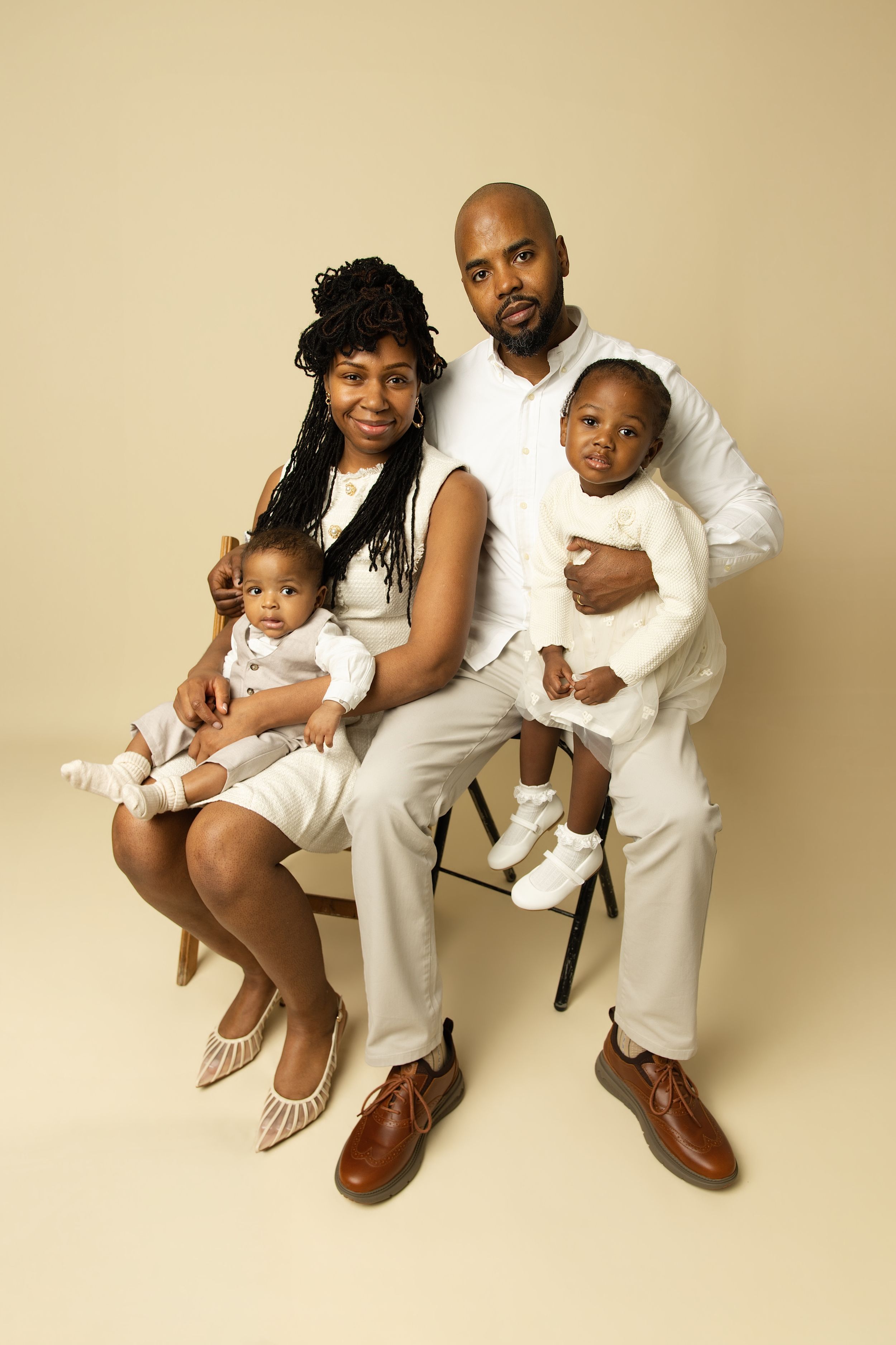 A series of four studio portraits showing a family in white outfits sitting and posing together against a beige backdrop.