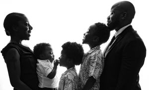 A black and white silhouette portrait of a family in profile against a bright white background.