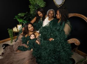 A glamorous family portrait with women in elegant emerald green gowns posing together on an antique settee.