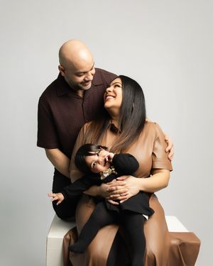 A joyful family moment captured against a white background as they embrace and laugh together.