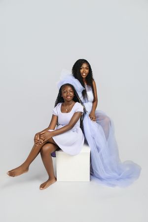 Artistic studio portraits in white clothing against light background show elegant poses with flowing blue fabric accents.