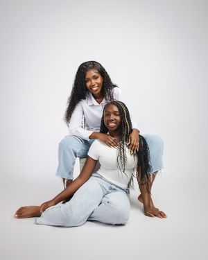 Two people wearing matching white loungewear outfits pose playfully together against a light background.