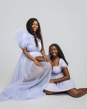 A maternity photoshoot featuring flowing white sheer fabric and intimate poses against a light gray background.