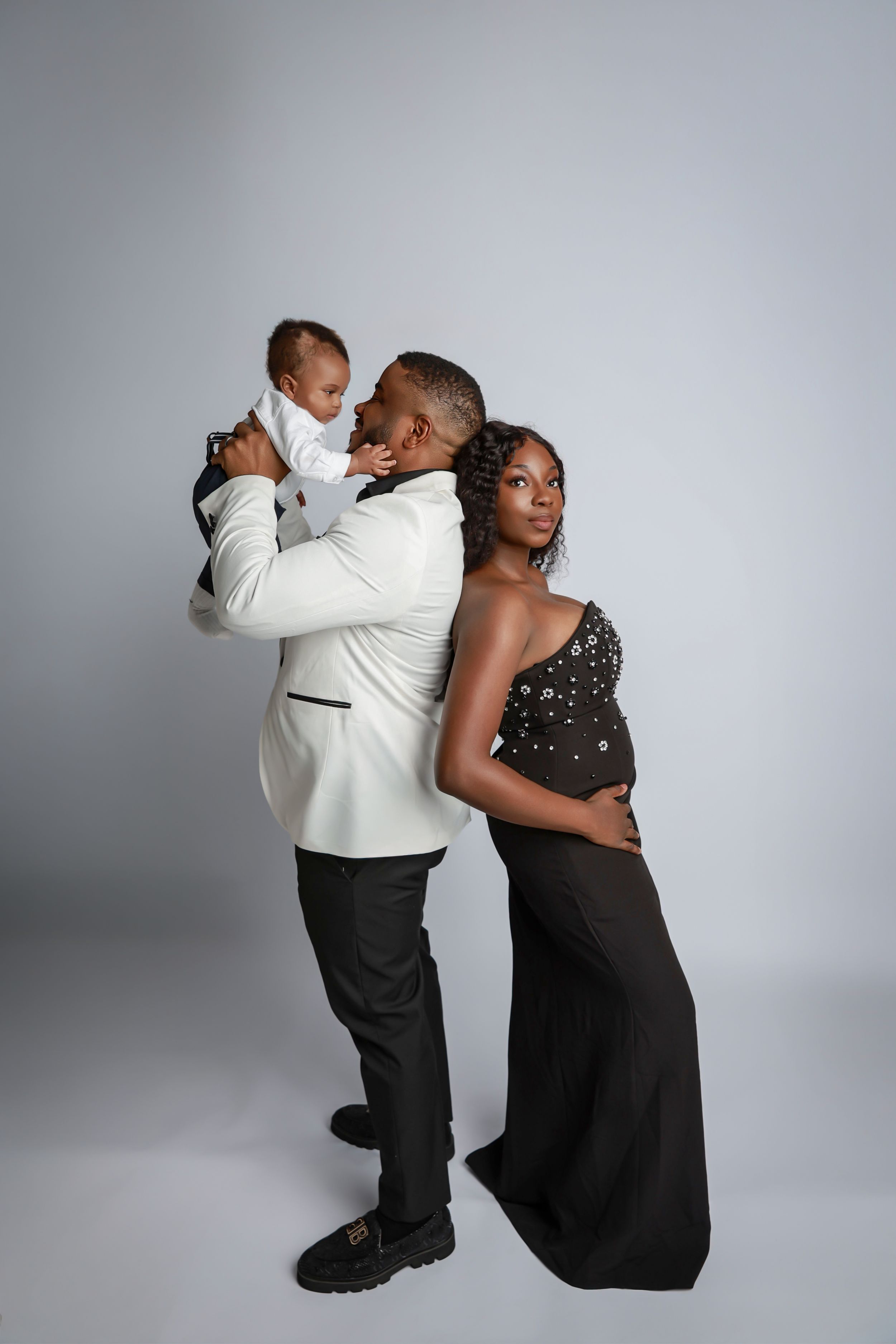 A couple in formal attire shares an intimate dance pose against a gray studio backdrop.