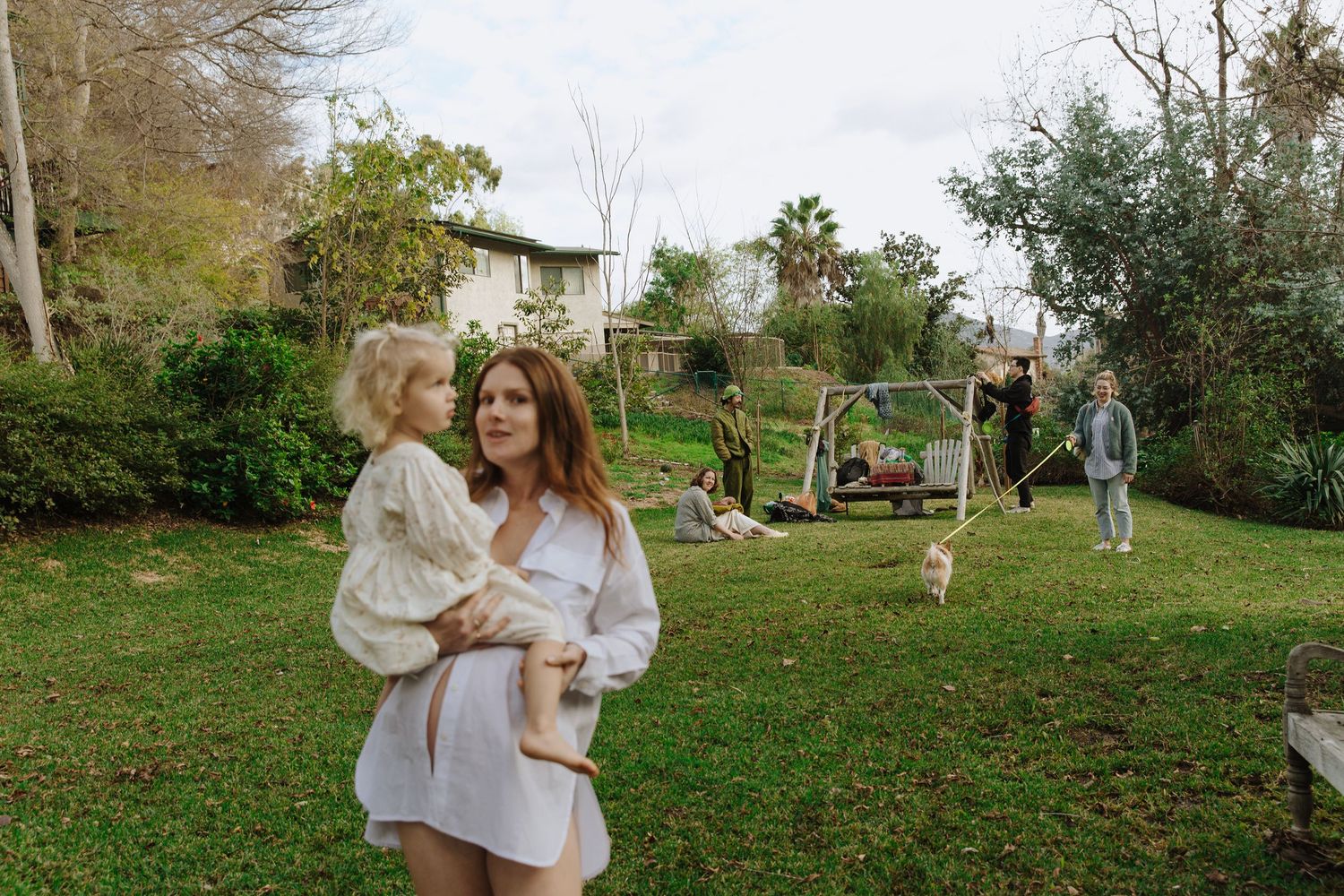 Outdoor family scene in a backyard with playground equipment visible in background.