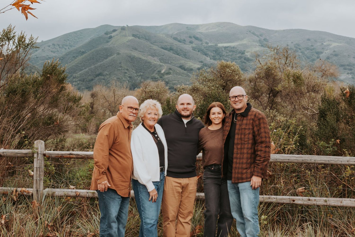 Extended family group poses together on hillside path with mountain views.