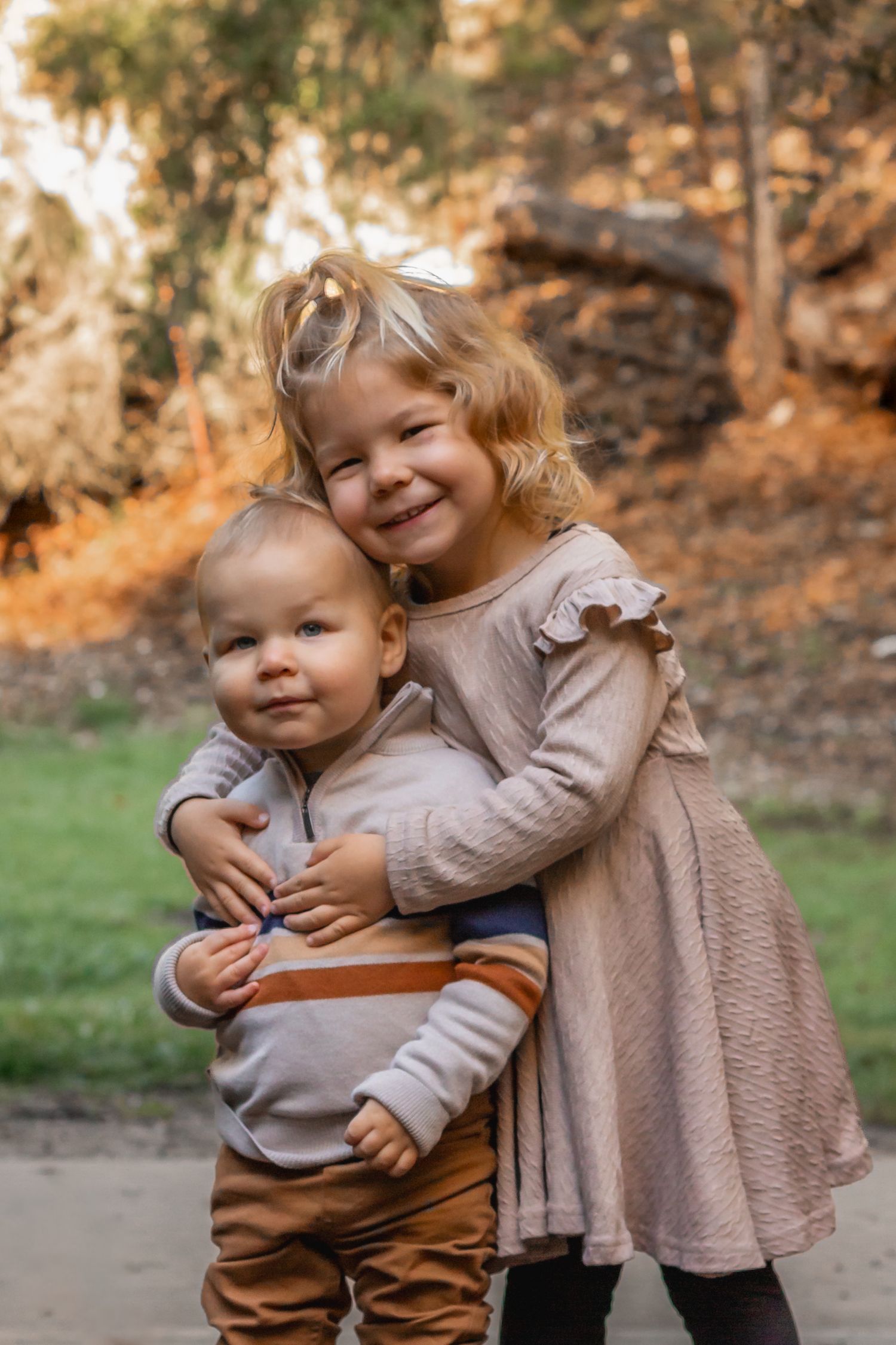 Two young children hugging and smiling together in outdoor fall setting. Lompoc, Santa Barbara, and San Luis Obispo County Photographer.