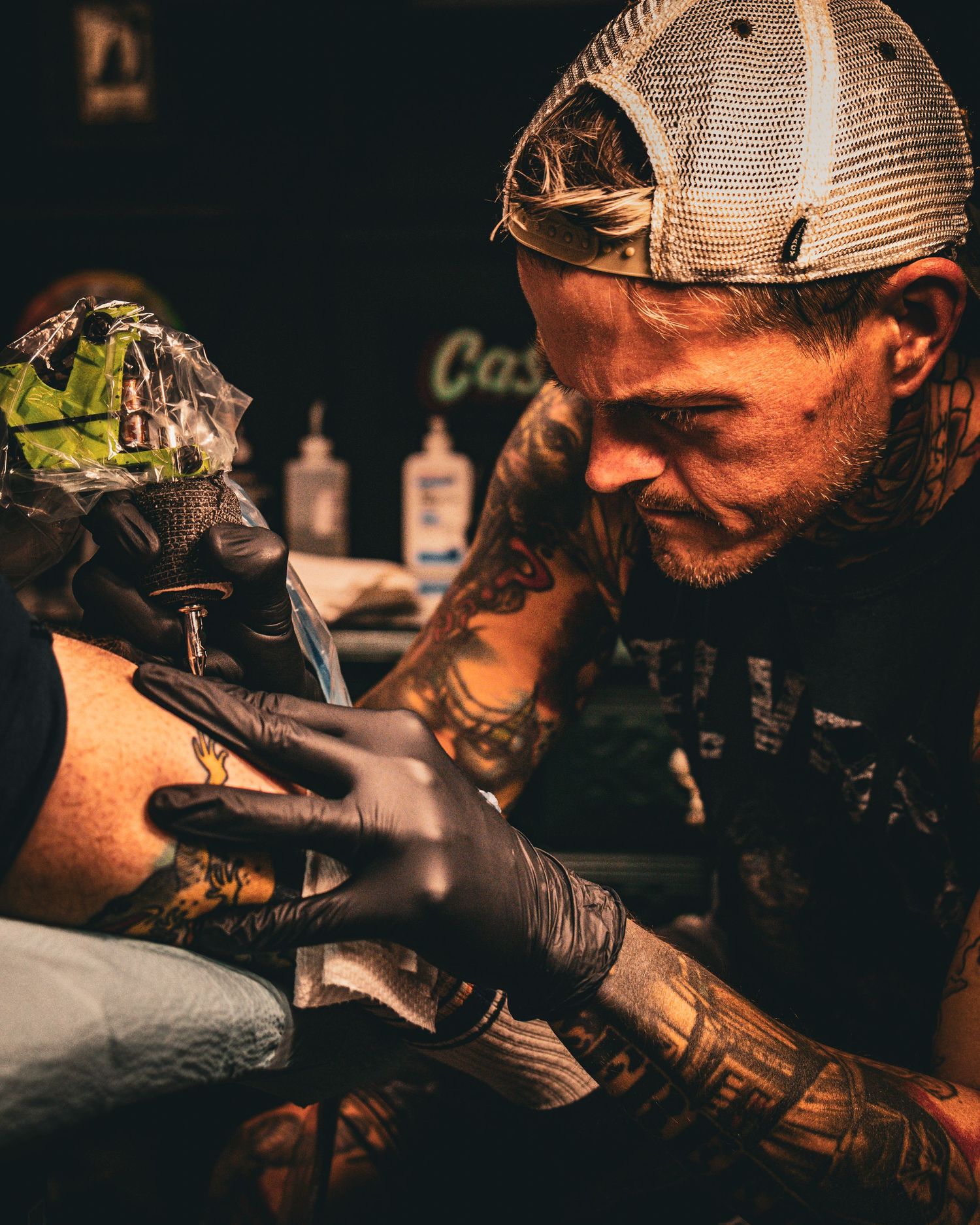 Close-up shots of tattoo artist working in dark studio setting.