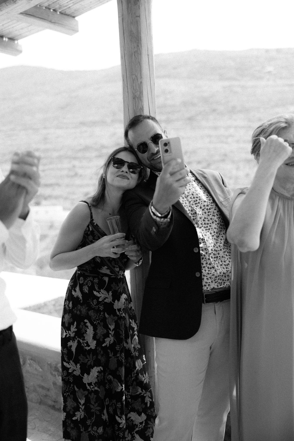 Group of stylishly dressed guests enjoying drinks on an outdoor terrace. Destination wedding photographer Kythnos