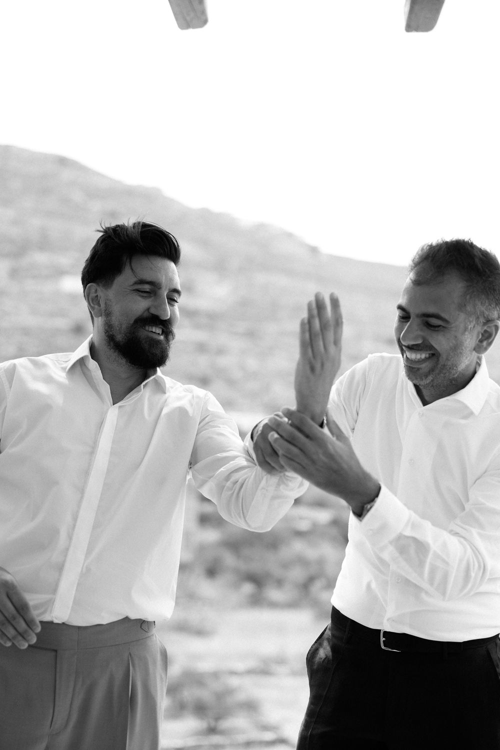 Two people in white shirts sharing an enthusiastic moment outdoors.