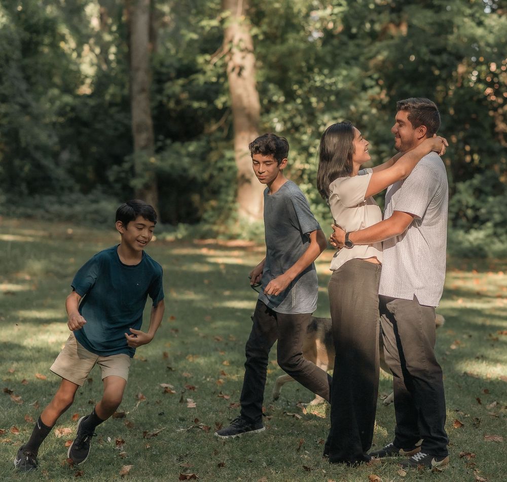 Family members sharing joyful moments together in a park setting on a sunny day.
