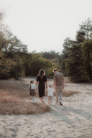 A group walks together along a sandy path through trees and brush at sunset in a natural setting.