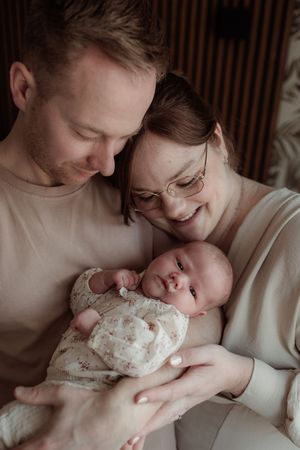 A tender moment between parents and their newborn baby captured in a series of intimate sepia-toned photographs.