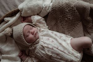 A collage of seven intimate newborn photography shots showing baby details and swaddled poses in neutral tones.