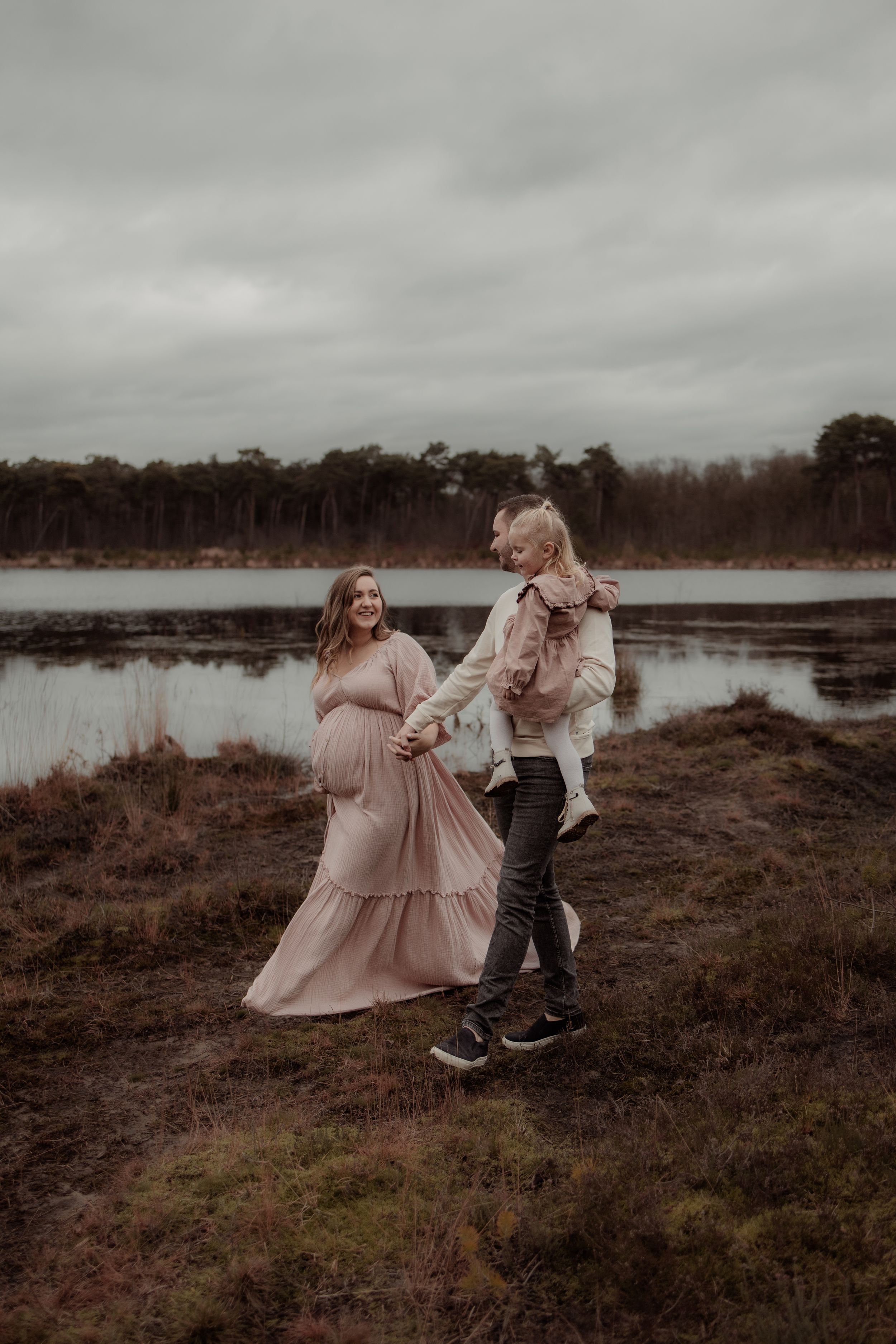 A couple in formal attire dances together on a misty moorland with dramatic cloudy skies in the background.