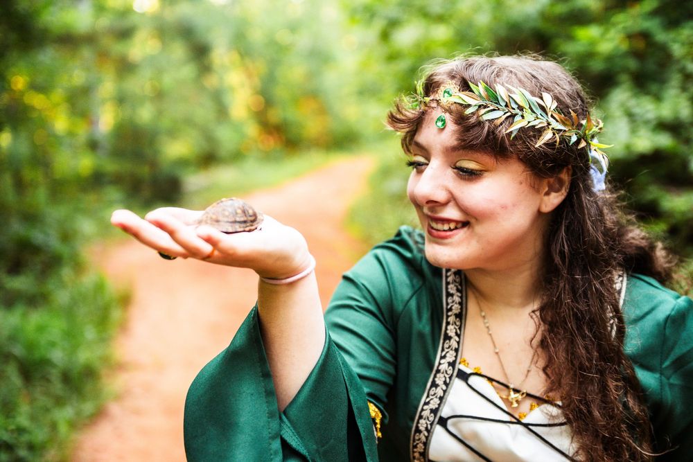 A couple in a lush green forest setting share an intimate moment during an outdoor photo session.