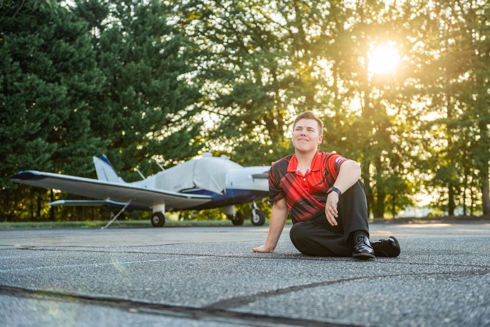Person lying on concrete surface at sunset with model airplane visible in dramatic lighting.