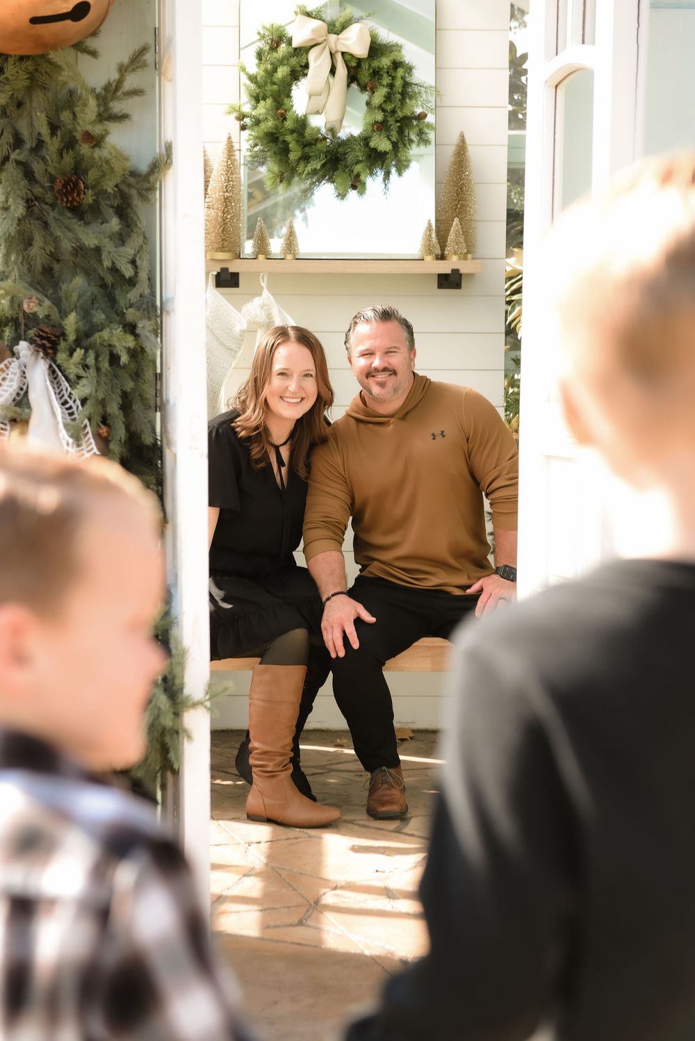 A festive front porch decorated for the holidays with a green wreath and rustic Christmas decor.