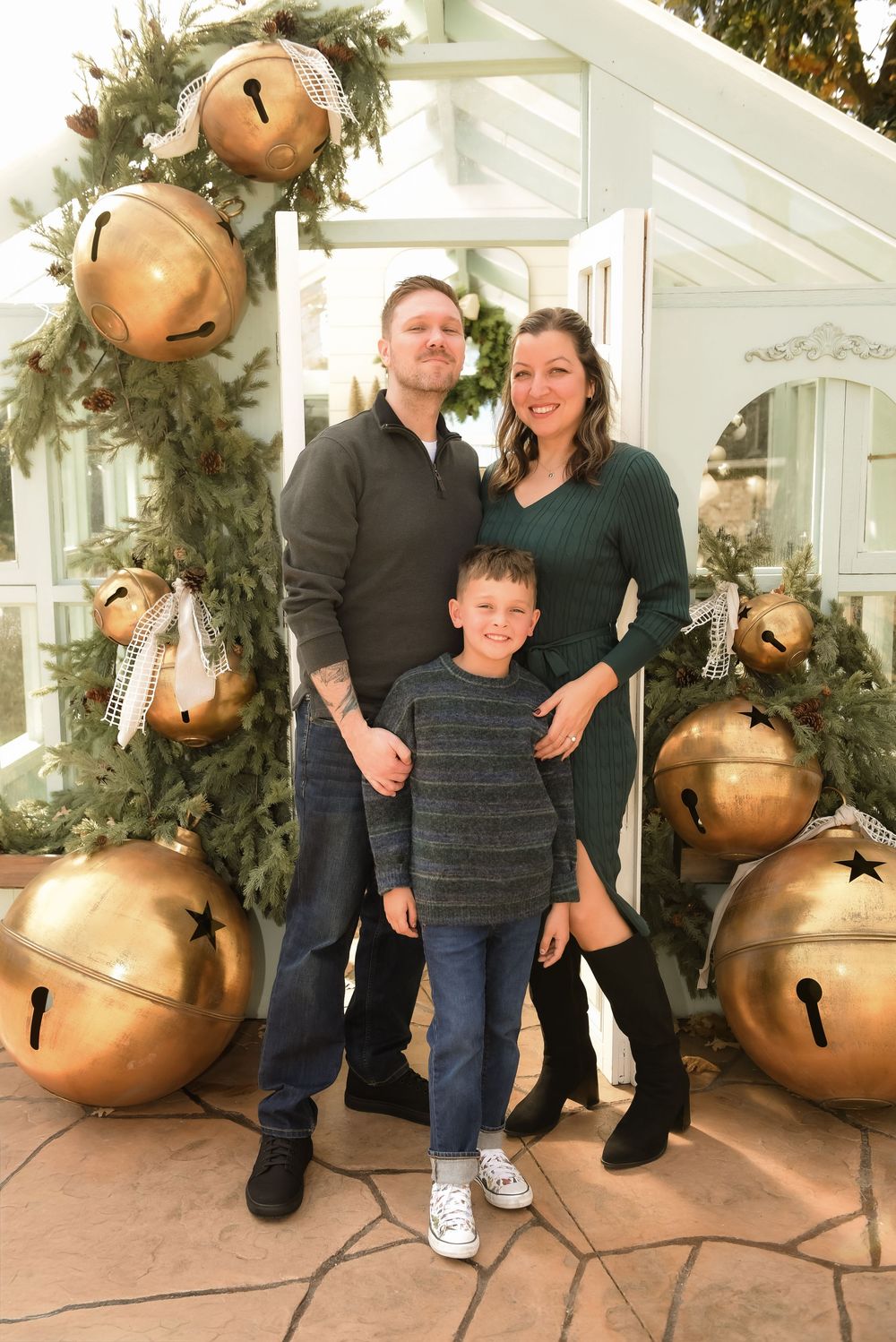 Family poses in front of large gold bells and evergreen garland for holiday photos in five sequential shots.