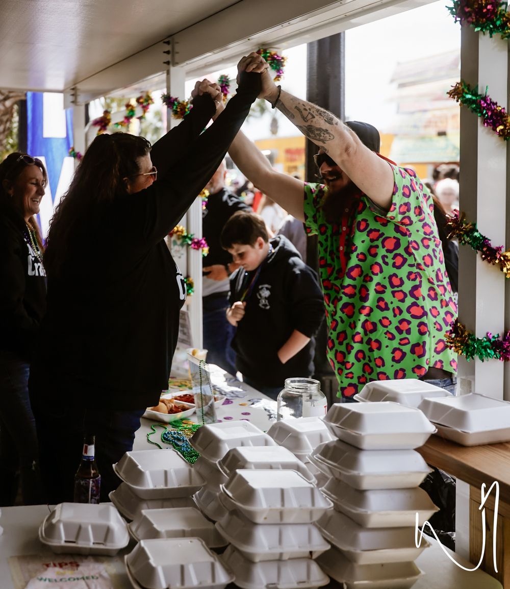 People line up at a buffet serving station with multiple chafing dishes and festive holiday decorations.