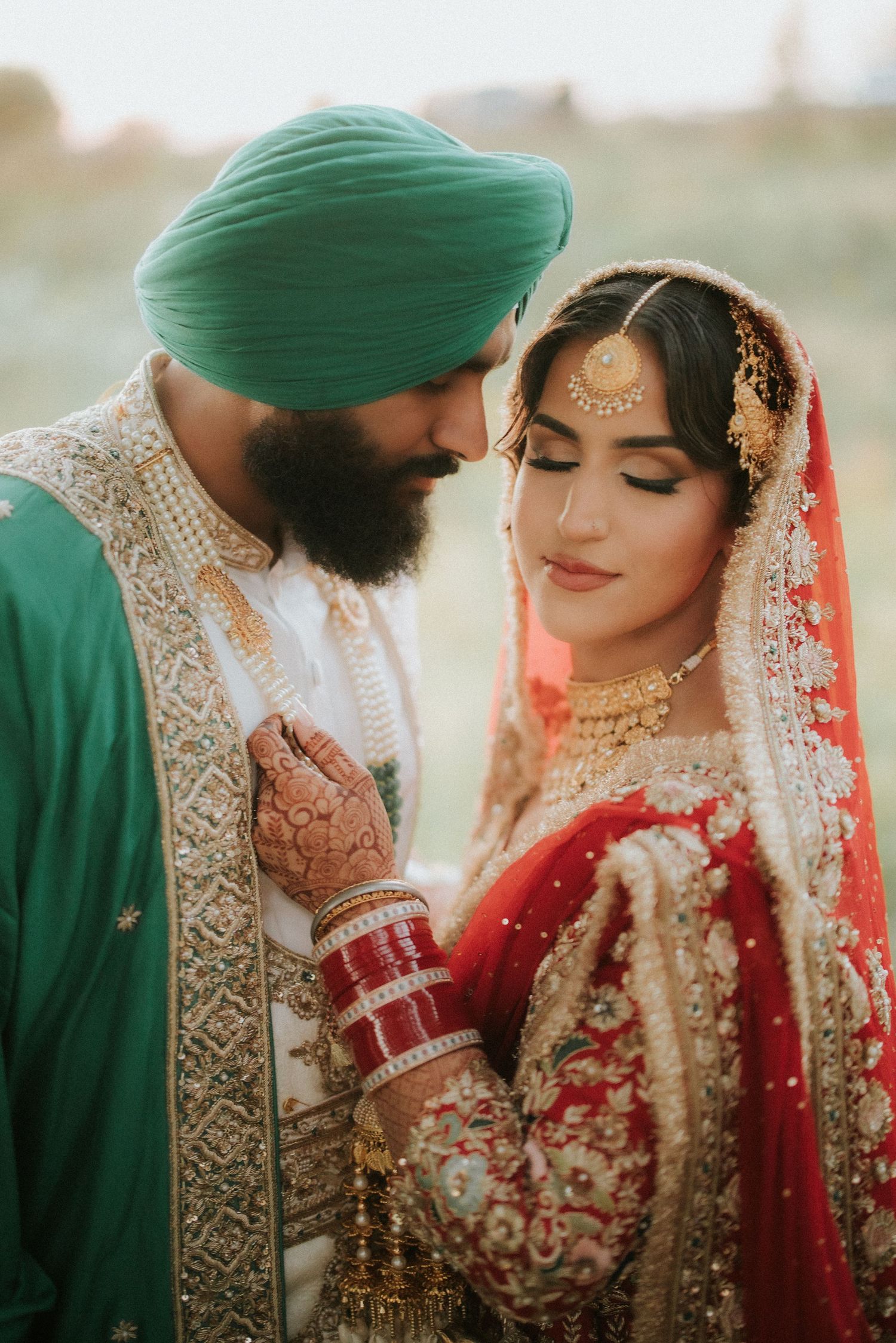 A series of romantic moments captured between a couple in traditional Sikh wedding attire with red and gold details.