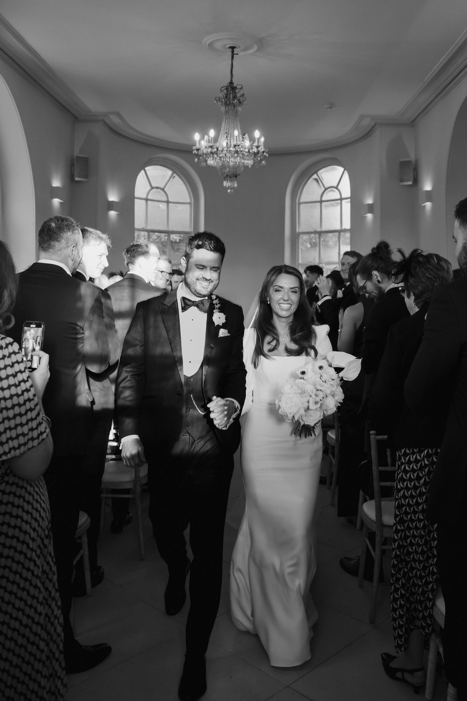 bride and groom coming down aisle as husband and wife as their guest cheer for them at Iscoyd park
