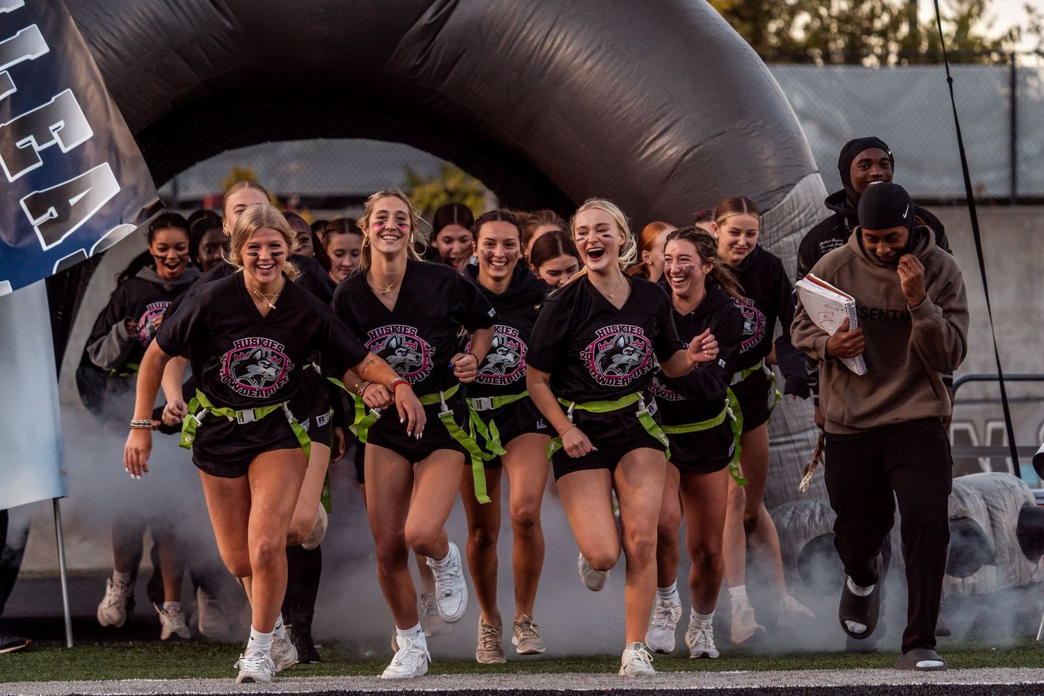 A group of cheerleaders perform synchronized crouching poses during an outdoor practice session.