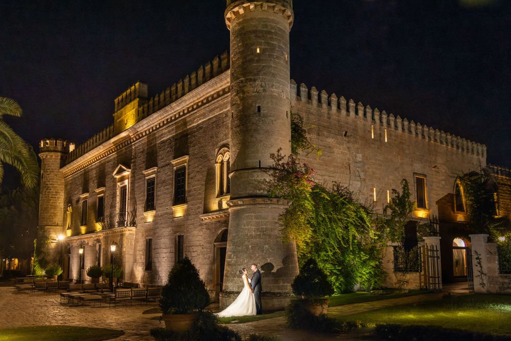 Bride and groom in night shot outside grand Italian castle, in Puglia, Italy