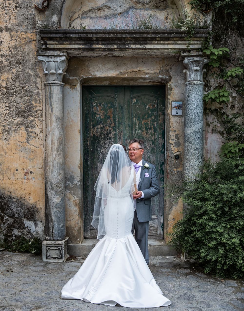 Artistic shot of bride and groom framed by medieval archway on Amalfi coast, Italy