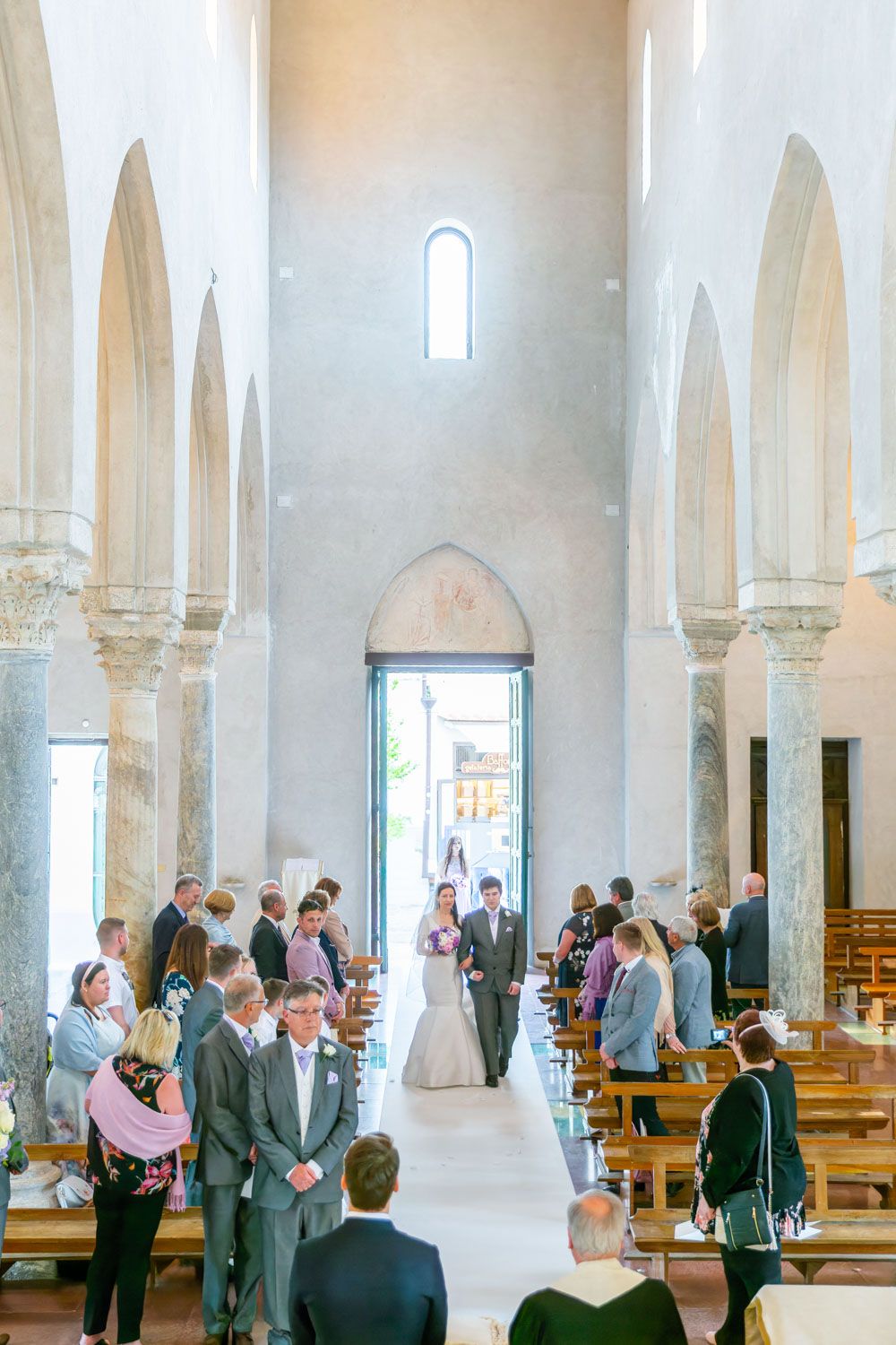 Bride walks down the isle of medieval church in Ravello, Amalfi, Italy at her destination wedding