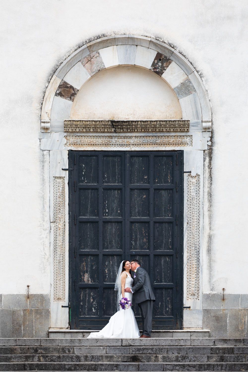 Bride and groom portrait framed by historic archway in Ravello, Italy for their destination wedding