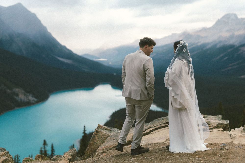 candid photo of bride and groom casually chatting above Peyto Lake during their Banff elopement