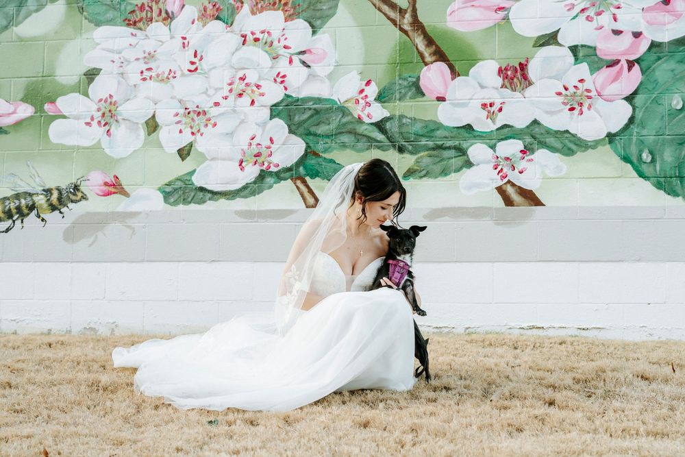 Wedding couple poses in front of a floral mural wall with pink and green botanical designs.