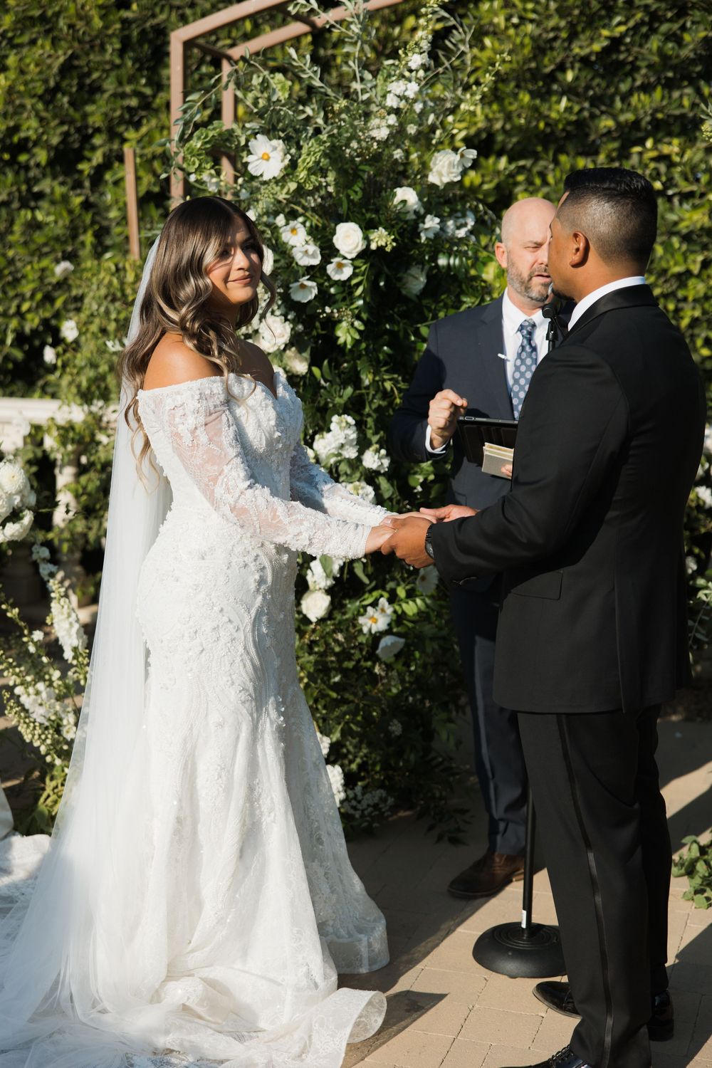 Bride and groom holding hands during their ceremony at Tuscan Rose Ranch in Santa Paula, California