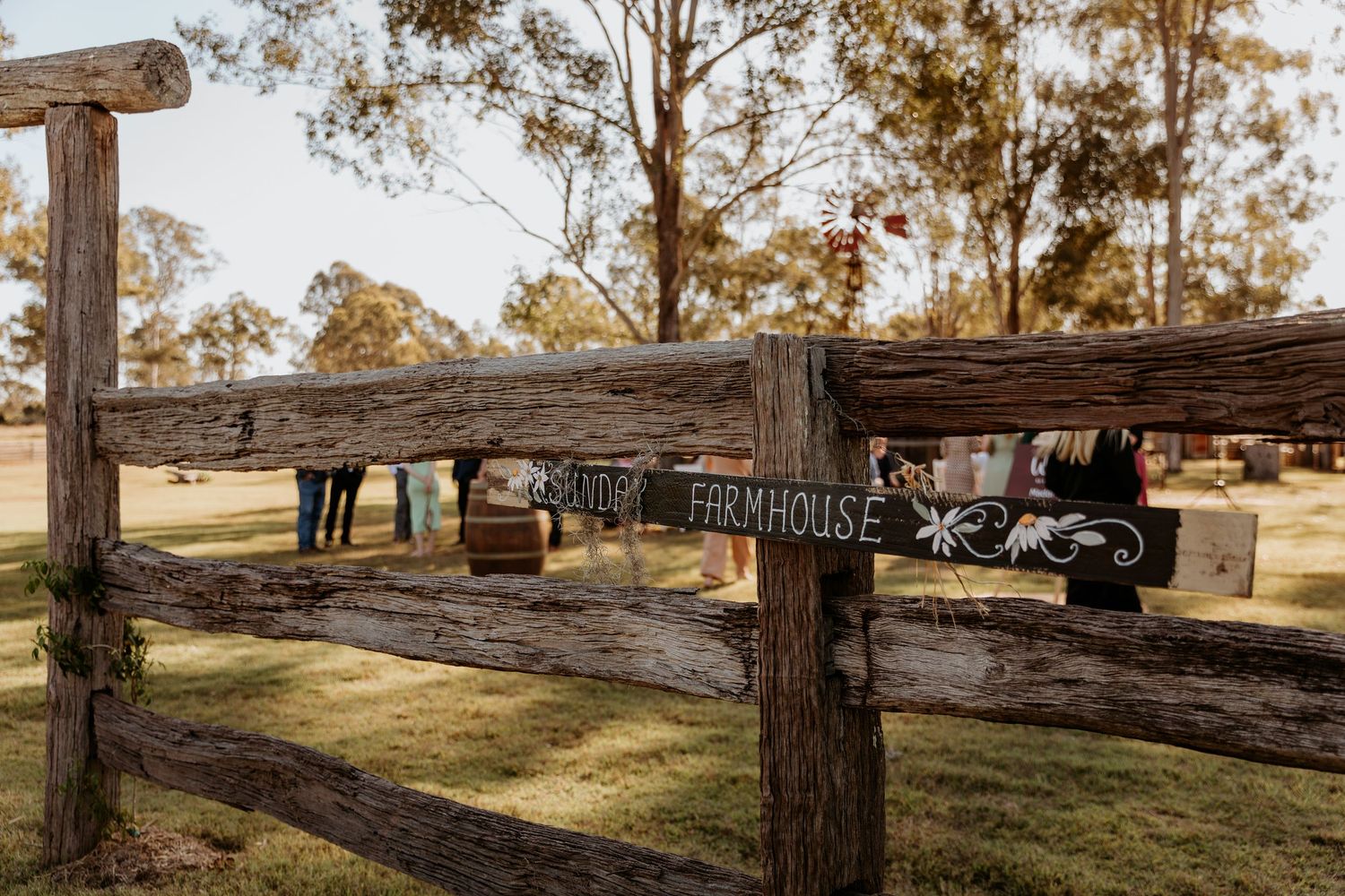 Panoramic view of rustic outdoor wedding venue with wooden fencing and trees.