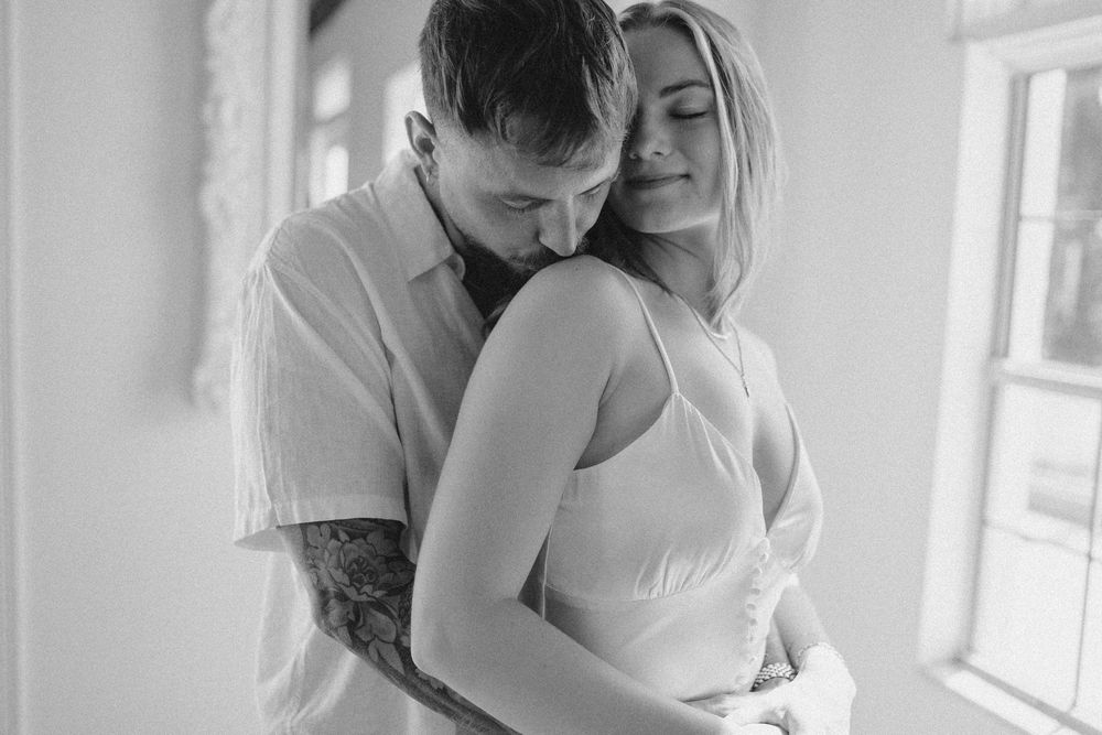 Black and white intimate portrait with natural window lighting.