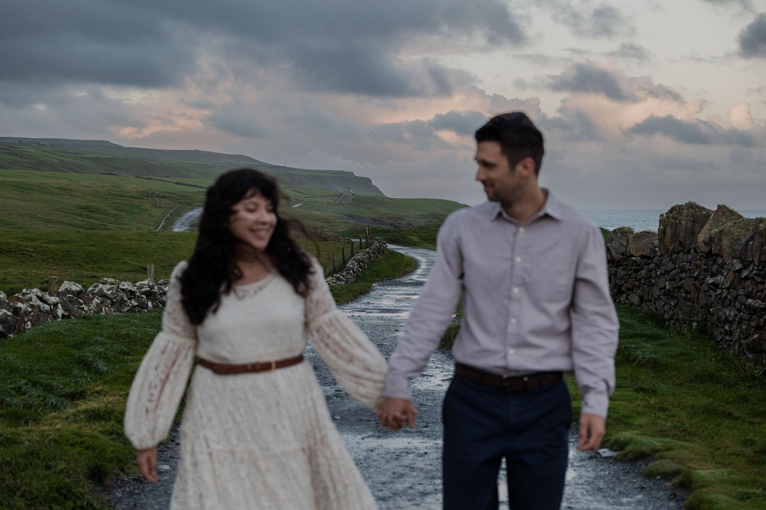 adventure session couple walking along Cliffs of Moher coastline at sunrise