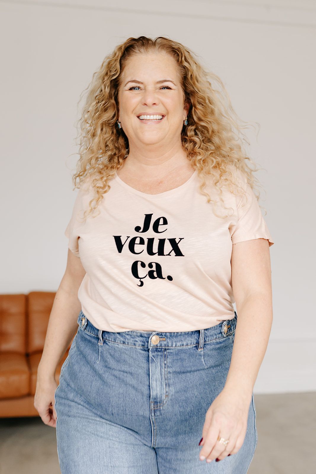 A person wearing a pink t-shirt and jeans poses in different positions showing off a casual outfit.