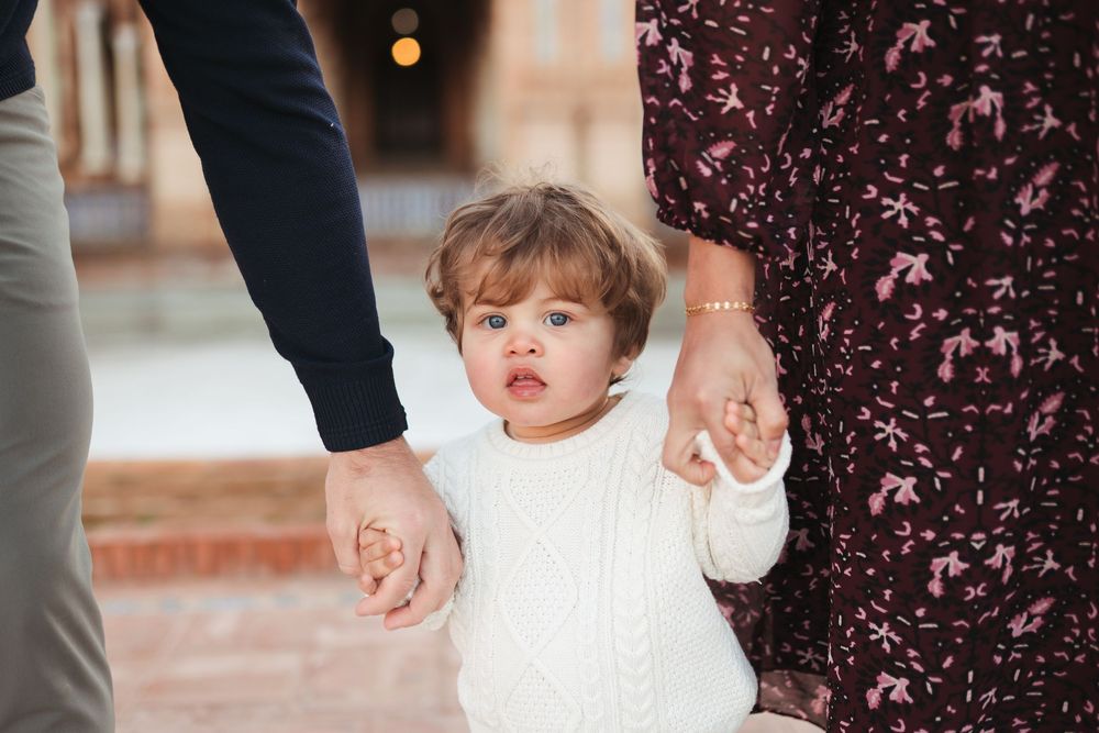 Small child holding hands with parents while walking at historic Plaza de España.