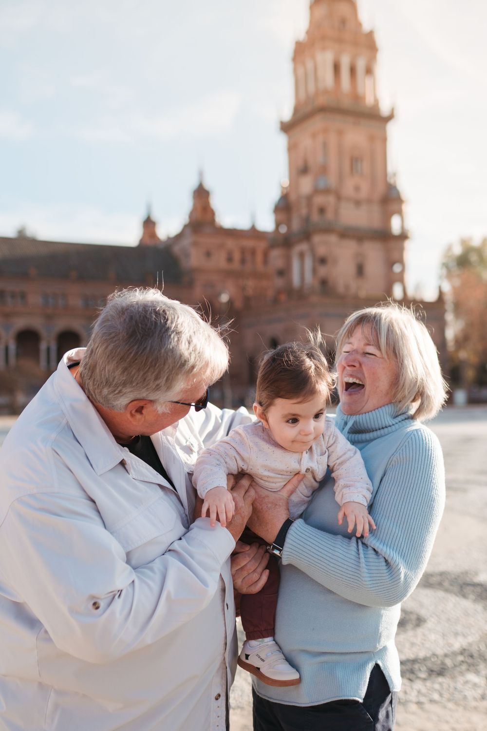 Joyful multi-generational family moment captured in front of Plaza de España tower.
